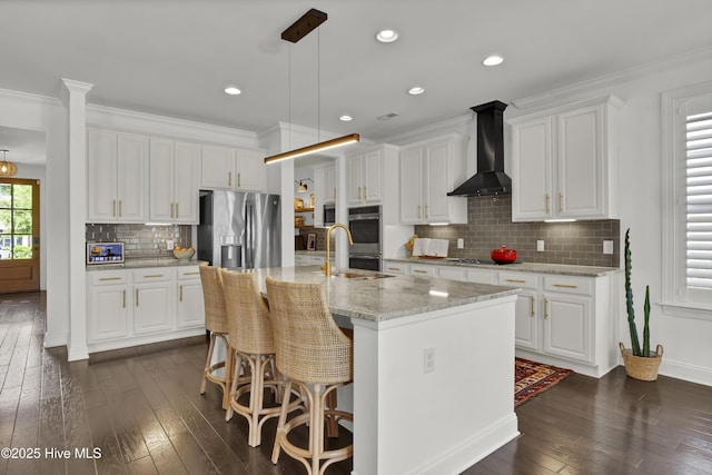 kitchen featuring white cabinets, stainless steel appliances, wall chimney range hood, and dark wood finished floors