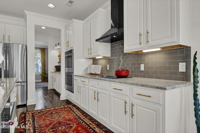 kitchen with white cabinets, wall chimney exhaust hood, stainless steel appliances, and visible vents