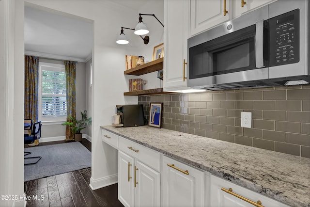 kitchen featuring stainless steel microwave, white cabinetry, open shelves, and baseboards