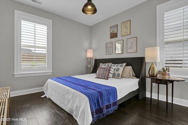 bedroom featuring baseboards, multiple windows, and wood finished floors