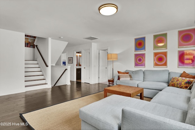 living room featuring visible vents, wood finished floors, baseboards, and stairs