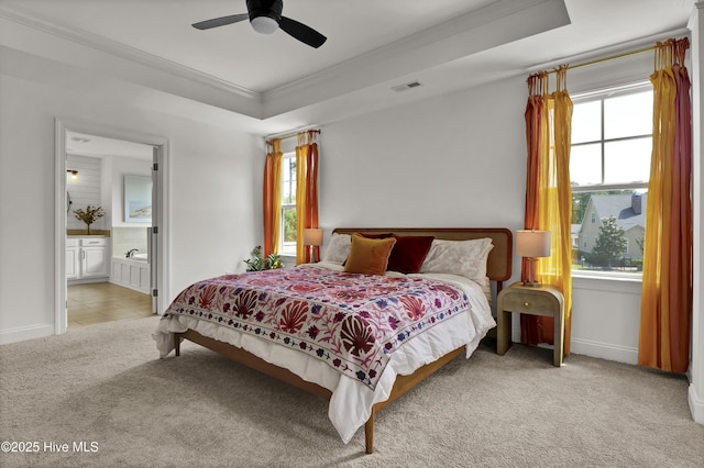carpeted bedroom featuring crown molding, a raised ceiling, baseboards, and multiple windows