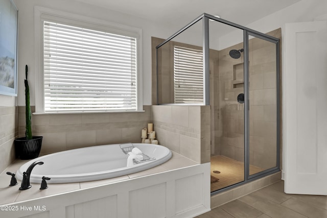 bathroom with a shower stall, a healthy amount of sunlight, and a bath