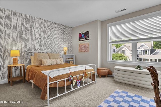 carpeted bedroom featuring baseboards, an accent wall, visible vents, and wallpapered walls