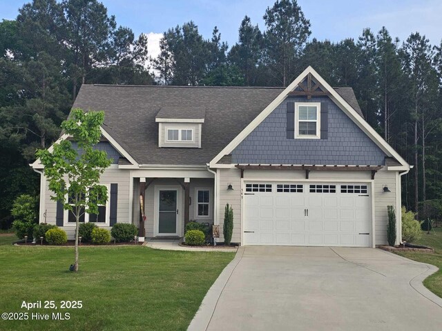 craftsman-style house with a garage, driveway, roof with shingles, and a front yard