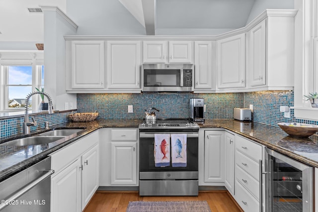 kitchen with stainless steel appliances, a sink, wine cooler, and white cabinetry