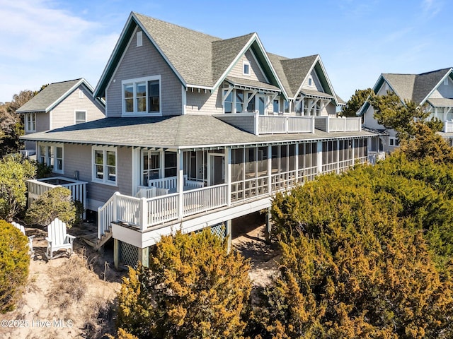 rear view of house featuring roof with shingles, a sunroom, and a balcony