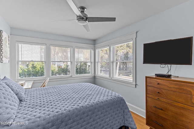 bedroom with wood finished floors, baseboards, and a ceiling fan
