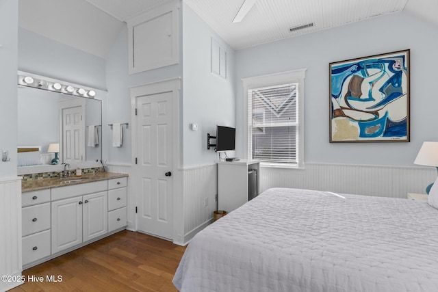 bedroom featuring a sink, a wainscoted wall, dark wood-style floors, and lofted ceiling