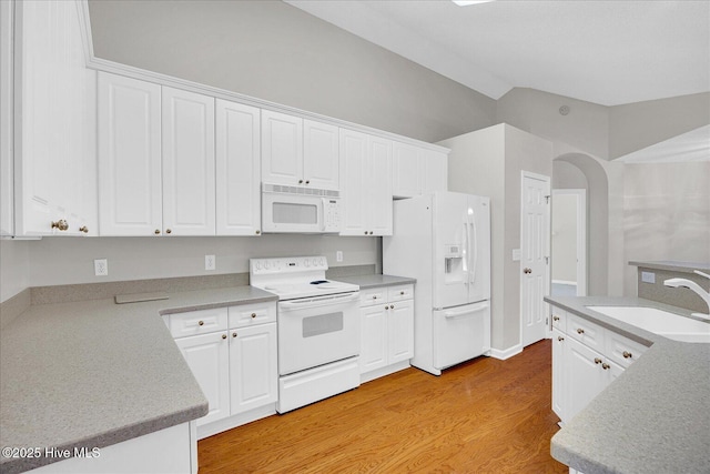 kitchen with a sink, white cabinets, white appliances, and lofted ceiling