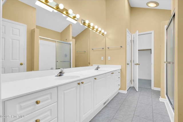 bathroom featuring a sink, tile patterned flooring, double vanity, baseboards, and a shower stall