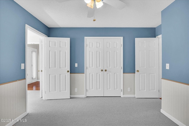unfurnished bedroom with carpet floors, wainscoting, and a closet