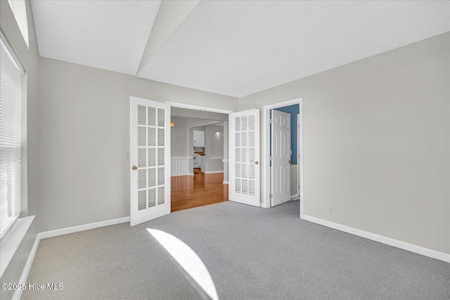 empty room featuring french doors, a heating unit, baseboards, and carpet floors