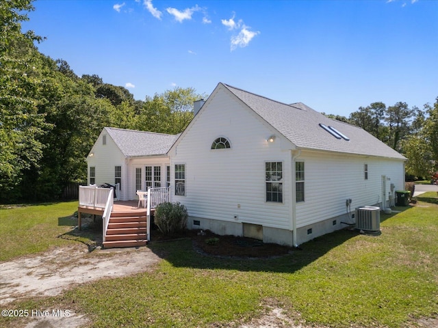 rear view of property featuring a yard, cooling unit, a wooden deck, and a shingled roof