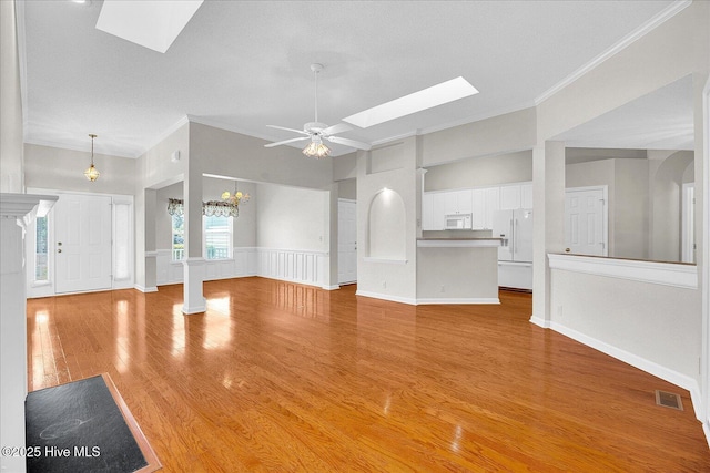 unfurnished living room featuring a skylight, crown molding, light wood-style floors, and a ceiling fan