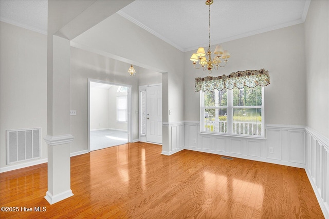 unfurnished dining area with visible vents, a healthy amount of sunlight, an inviting chandelier, and wood finished floors
