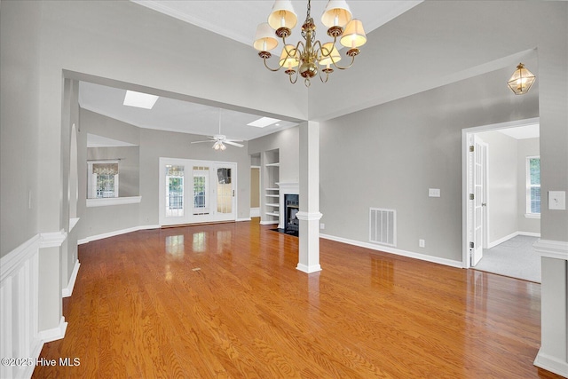 unfurnished living room with a fireplace with flush hearth, visible vents, built in features, and wood finished floors
