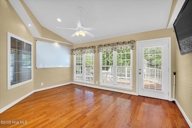unfurnished room featuring vaulted ceiling, a ceiling fan, wood finished floors, and a healthy amount of sunlight