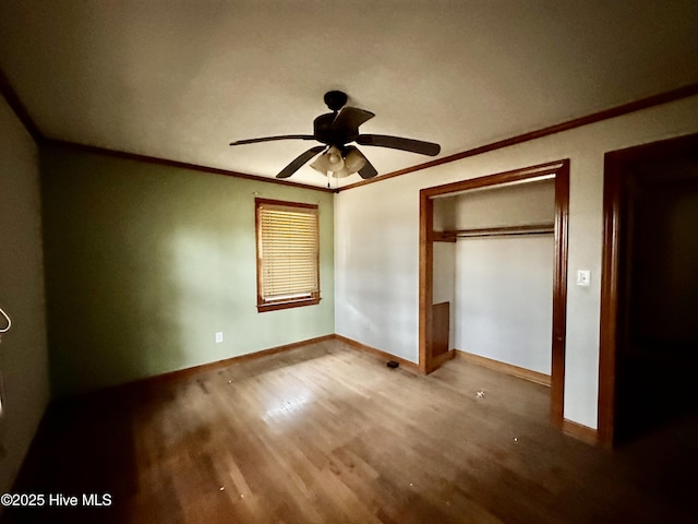 unfurnished bedroom featuring baseboards, ornamental molding, a ceiling fan, and wood finished floors