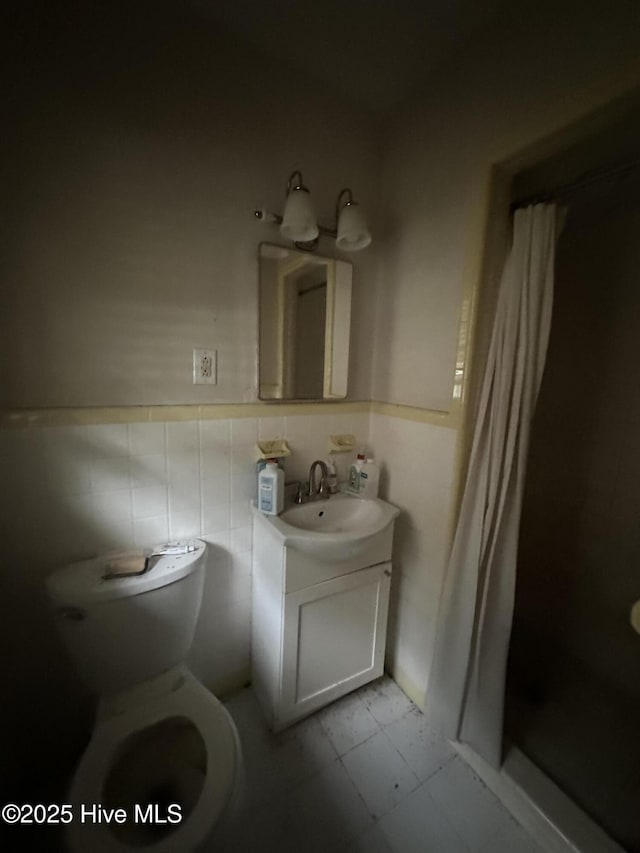 bathroom featuring vanity, toilet, a wainscoted wall, tile patterned floors, and a shower stall