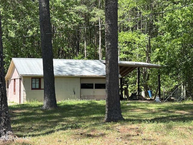 view of side of home with a lawn, concrete block siding, an attached garage, and metal roof