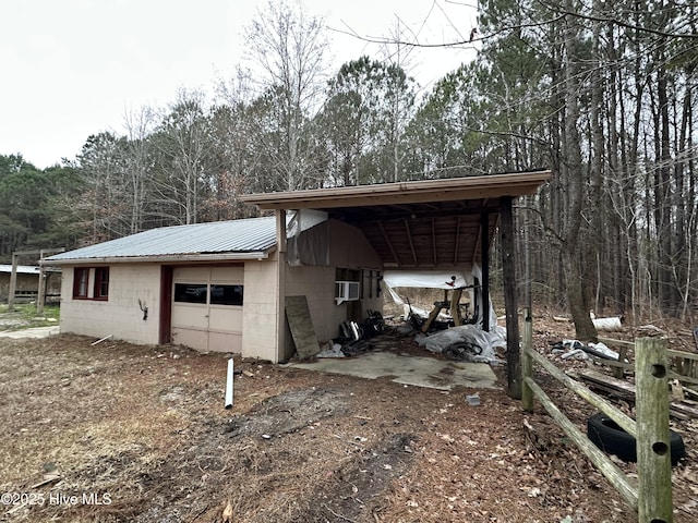 exterior space featuring concrete block siding, an outbuilding, metal roof, and a garage