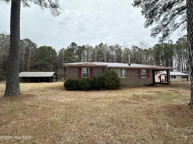 view of property exterior with brick siding, a detached carport, and a lawn