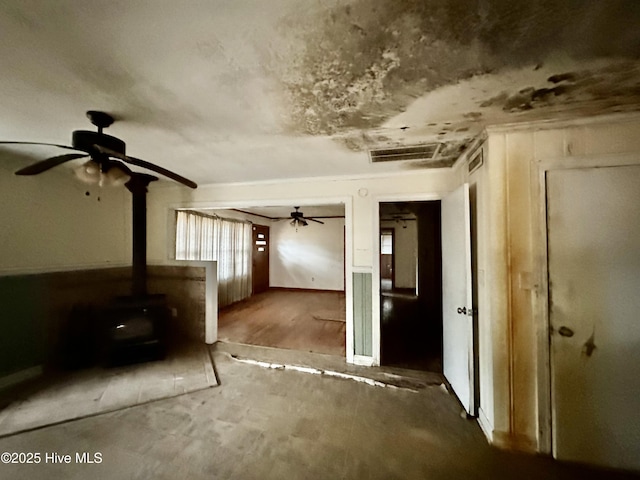 interior space with a ceiling fan and a wood stove