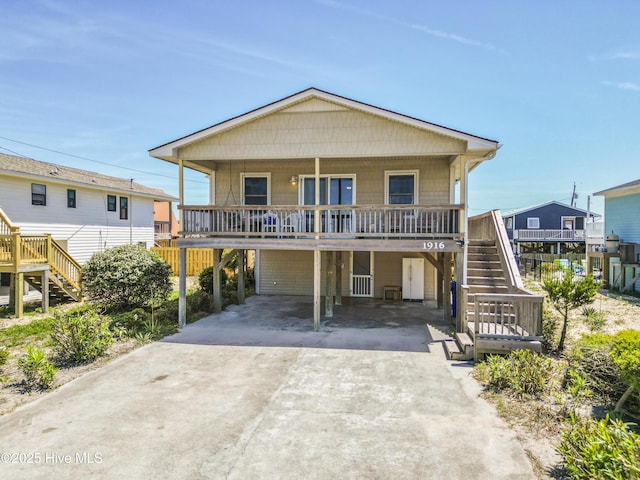 beach home with a carport, stairs, concrete driveway, and a porch