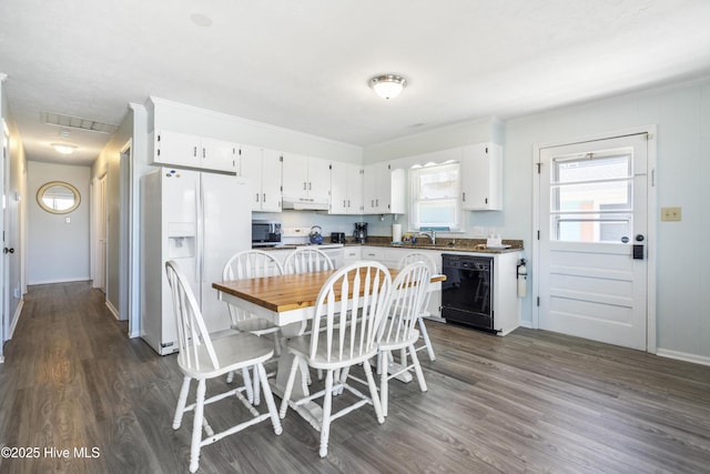 kitchen with dark wood-style flooring, dark countertops, white appliances, white cabinetry, and under cabinet range hood