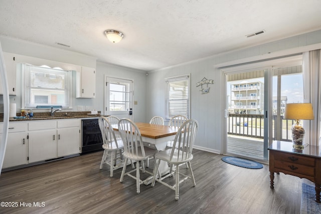 dining space featuring crown molding, a textured ceiling, dark wood finished floors, and visible vents