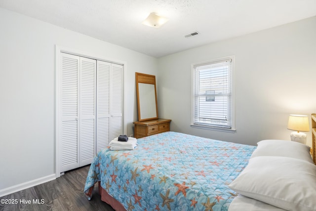 bedroom with dark wood-type flooring, baseboards, visible vents, and a closet