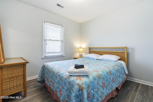 bedroom featuring baseboards, wood finished floors, and visible vents