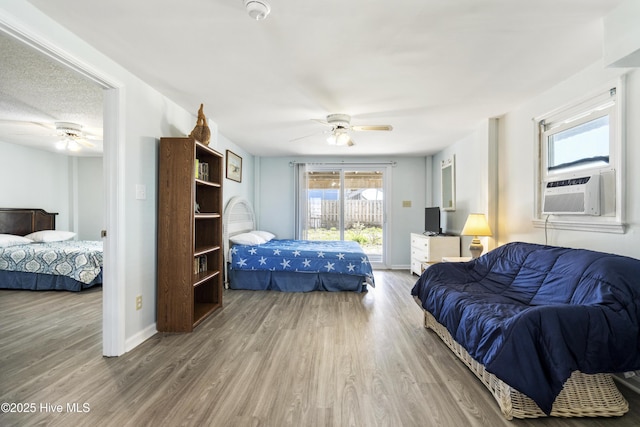 bedroom with access to outside, cooling unit, a ceiling fan, and wood finished floors