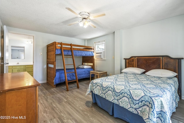 bedroom with a sink, a textured ceiling, wood finished floors, and cooling unit