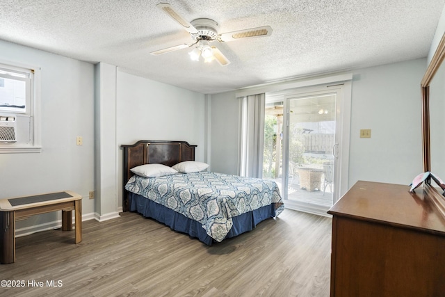 bedroom with a textured ceiling, a ceiling fan, wood finished floors, and access to exterior