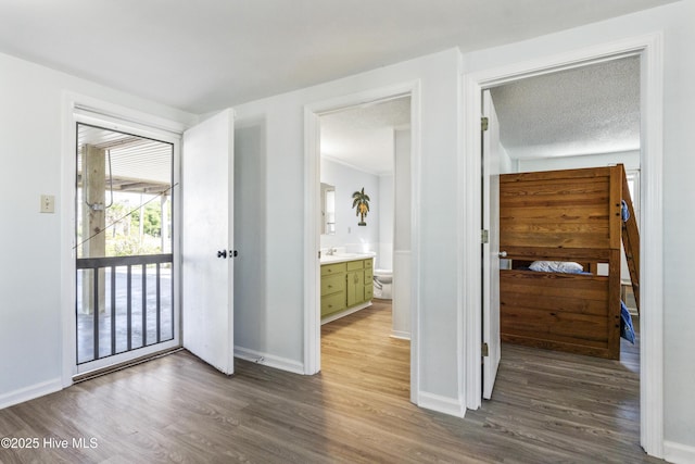 interior space featuring baseboards, a sink, access to exterior, and wood finished floors