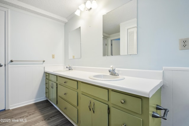 bathroom featuring double vanity, a textured ceiling, a sink, and wood finished floors