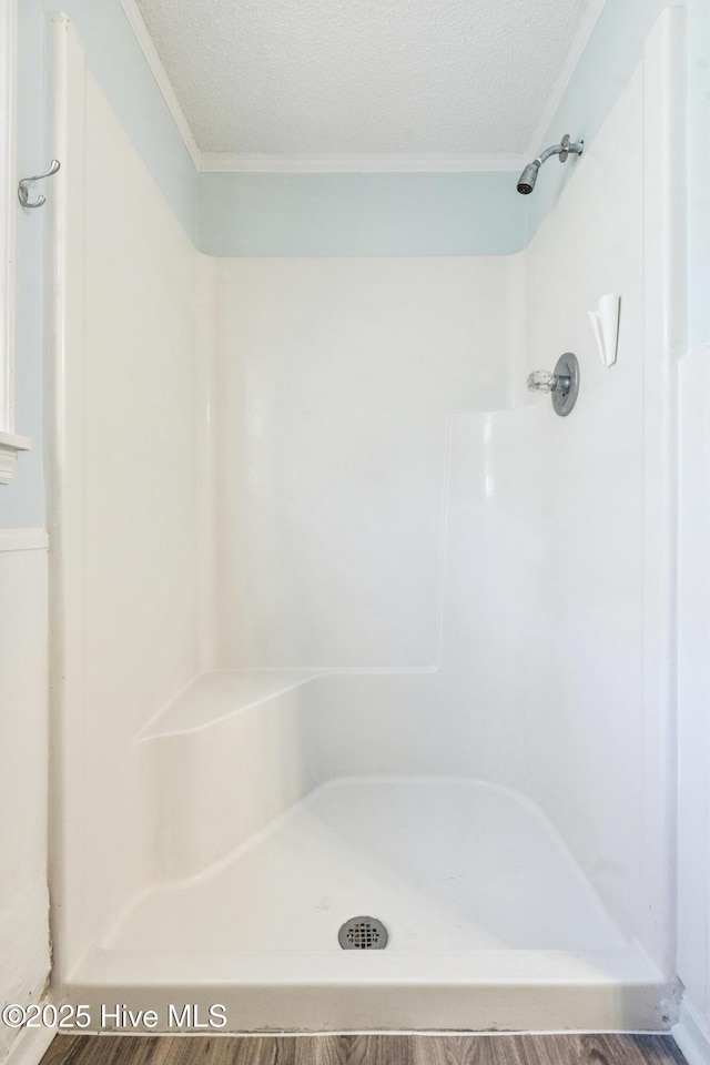 full bathroom featuring a textured ceiling, walk in shower, and ornamental molding