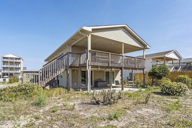 rear view of property featuring fence, a wooden deck, stairs, and a patio area