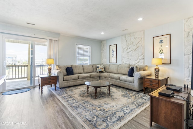 living area with recessed lighting, a textured ceiling, crown molding, and wood finished floors