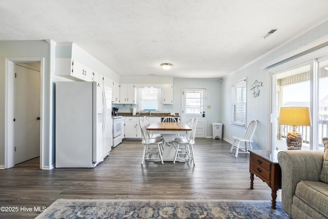 kitchen featuring white appliances, white cabinetry, a textured ceiling, and dark wood-style floors