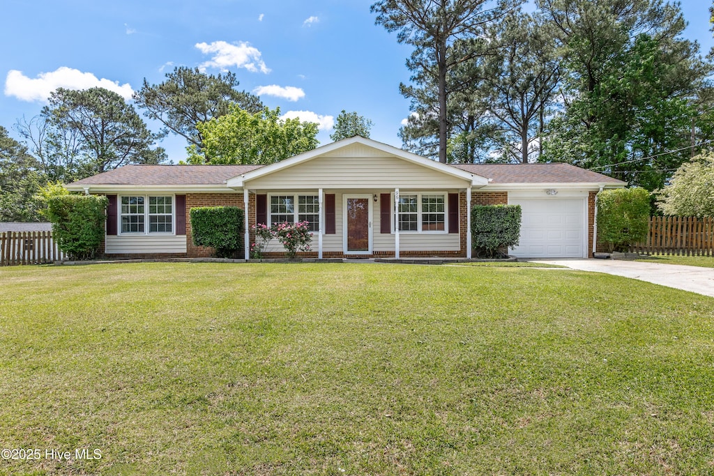 ranch-style house featuring fence, an attached garage, brick siding, a front yard, and concrete driveway