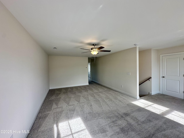 spare room featuring ceiling fan, light colored carpet, and baseboards