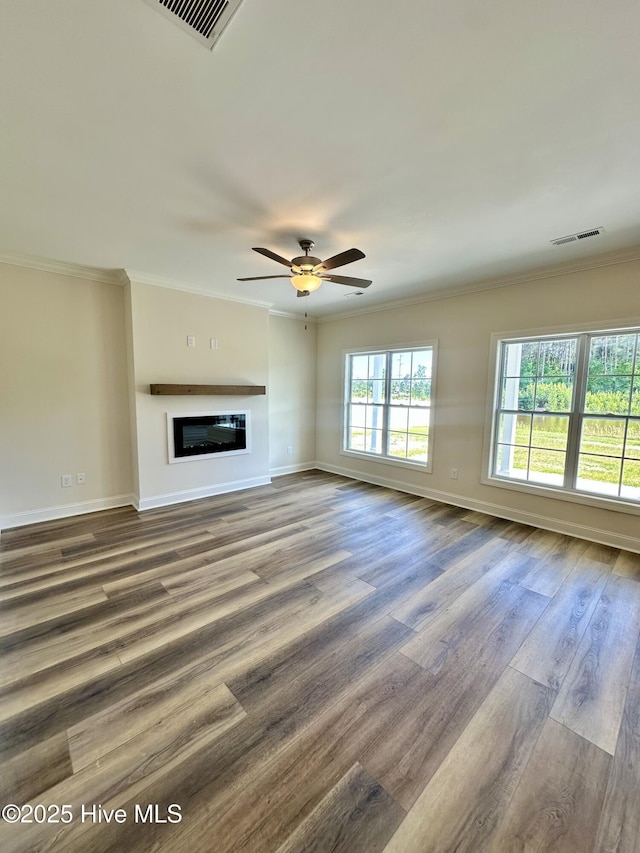 unfurnished living room with baseboards, ornamental molding, wood finished floors, and visible vents