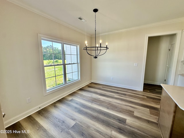 unfurnished dining area with crown molding, a chandelier, a healthy amount of sunlight, and dark wood finished floors