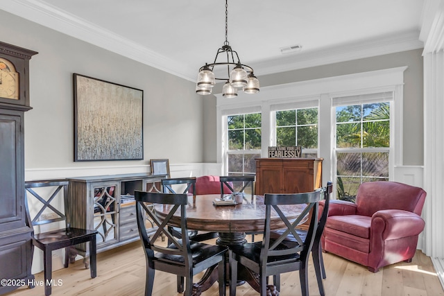 dining area with visible vents, ornamental molding, a wainscoted wall, and a healthy amount of sunlight