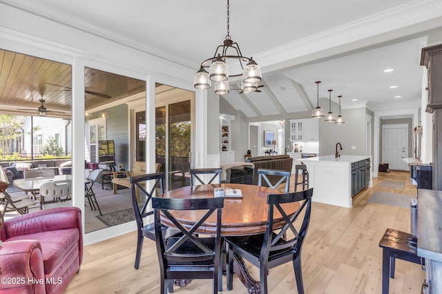 dining area with crown molding, lofted ceiling with beams, light wood-style flooring, and ceiling fan with notable chandelier