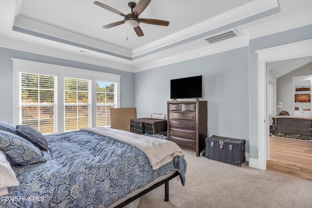 bedroom with visible vents, crown molding, a tray ceiling, and carpet floors