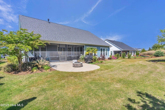 rear view of property with roof with shingles, a lawn, a sunroom, an outdoor fire pit, and a patio